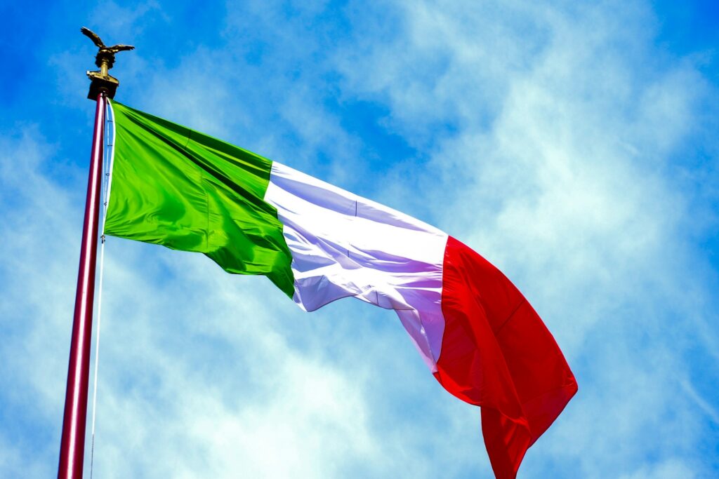 Bandiera italiana che sventola su un cielo azzurro.